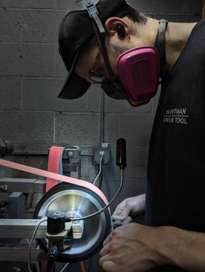 A young man grinding a knife